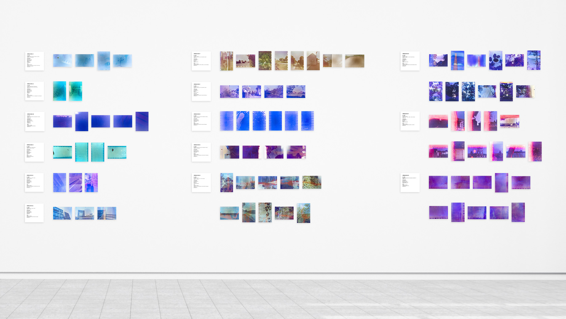 Frontale Ansicht einer Wand mit postkartengroßen Serienbildern, in Reihen angeordnet. Die Bilder sind in 14 Serien unterteilt. Sie zeigen visuelle Ergebnisse verschiedener fotografischer Zufallsexperimente.