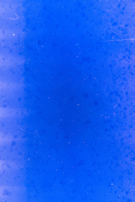 Monochrom blaues Bild mit kleinen dunklen Flecken. Am linken Rand verlaufen einige hellere, kurze, horizontale Streifen.
