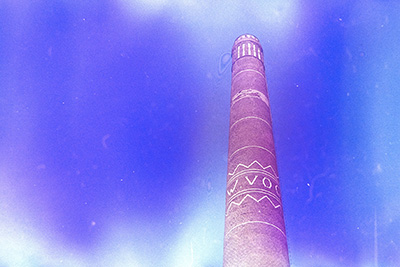 Querformat. Gleicher Schornstein erneut, diesmal mit einigen hellen Lichtflecken am oberen und unteren Bildrand. Der Himmel ist blau, überlagert von bläulichen Farbschleiern.